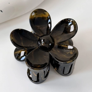 Détail d'une pince à cheveux en forme de fleur avec motif écaille et finition brillante