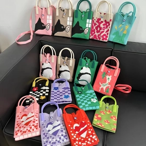 Mini sacs en tricot avec motifs de panda et fleurs présentés sur un canapé noir