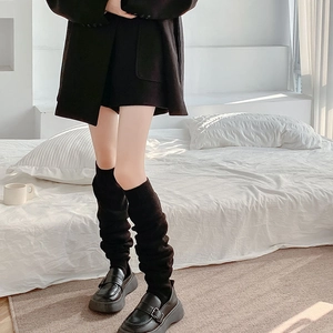 Close-up of black ribbed knit leg warmers with cozy slouchy style on a model
