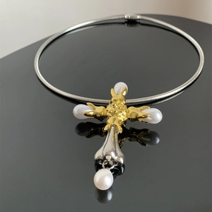 Macro detail of bicolour cross pendant with pearl on silver snake chain choker