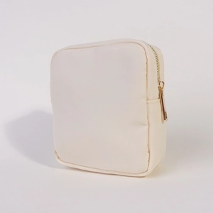 Detailed close-up of beige nylon cosmetic bag featuring a smooth gold metal zipper