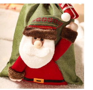 Close-up of green linen Christmas gift bag featuring a 3D Santa Claus holding a gift box