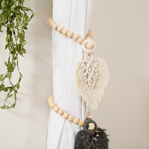 Detail of wooden beads and hand-woven beige cotton leaf tassel on a white curtain