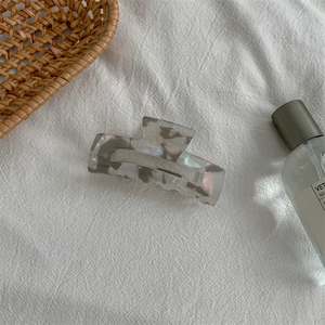 Detail of gray iridescent marble acetate hair claw clip on white fabric background