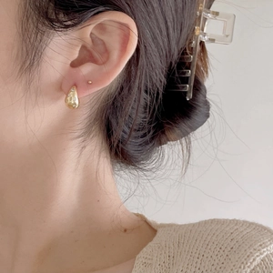 Close-up of a gold water-drop earring with micro-set zircon on a model ear
