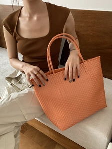 Detailed view of large orange woven tote bag with premium handmade texture and handle