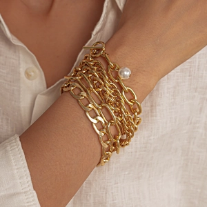 Detailed close-up of multilayer gold chain bracelets with pearl charm and OT toggle clasp