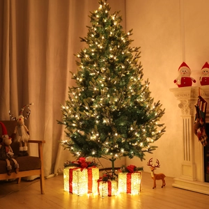 Close-up of lighted Christmas tree with warm LED string lights and glowing gift boxes