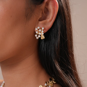 Detail of vintage flower leaf pearl drop earrings worn by a model in golden finish
