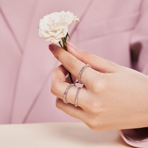Close-up of three stacked S925 silver rings with colorful zircon on a hand with white rose