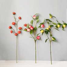 Detailed view of artificial fruit branches with red berries, peaches and yellow lemons