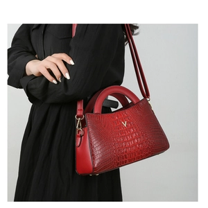 Detail of red crocodile texture handbag with gold V-metal logo and detachable strap