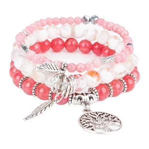 Close-up of pink and red beaded bracelets with Tree of Life and leaf silver charms
