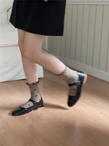Detail of brown polka dot crew socks with ruffled edges worn with black Mary Jane shoes