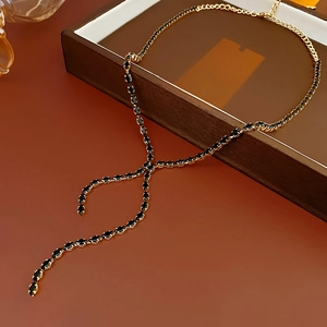Detail of gold-plated Y-shaped necklace featuring black marquise zircon stones and tassel