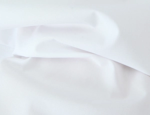 Macro detail of the white woven fabric texture showing fine weave and soft folds