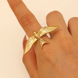 Detailed view of an adjustable golden swallow ring on a finger showing wing textures