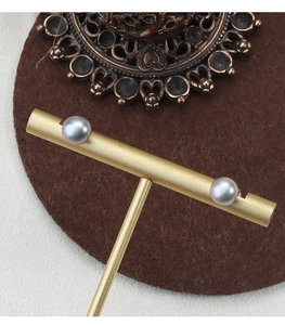 Macro shot of Madama grey pearl earrings on a gold T-stand with soft lighting