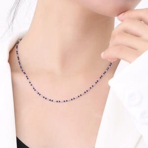 Detailed view of thin beaded chain necklace with blue and light blue beads on a model neck