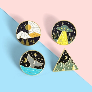 Enamel pins detail showing artistic whale tail and celestial patterns on pink and blue backdrop