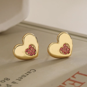 Elegant 18K gold plated heart stud earrings with red zircon stones on a book page