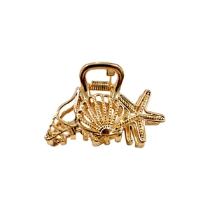 Detail shot of golden metal starfish and seashell hair claw clip with spring structure