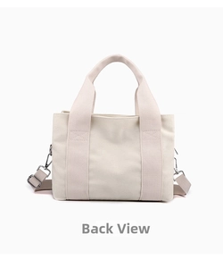 Rear view of an off-white canvas tote bag with adjustable shoulder strap and sturdy handles