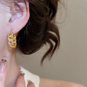 Detail of French vintage gold chain earrings with diamonds worn on the earlobe
