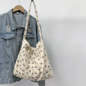 Detail of corduroy tote bag with yellow tulip print hanging on denim jacket