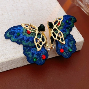 Détail de boucles d'oreilles papillon vintage avec broderie bleue et cristaux colorés