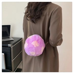 Close-up of purple plush crossbody bag with gold chain strap on professional outfit