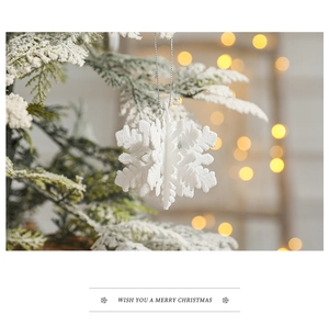 Sparkling white snowflake ornament with glitter texture hanging on Christmas tree branch