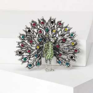 Exquisite peacock brooch with silver metal and green rhinestones on white background