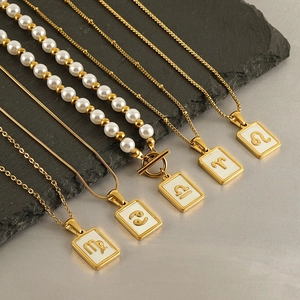 Golden stainless steel zodiac pendant necklace with white shell on grey stone background