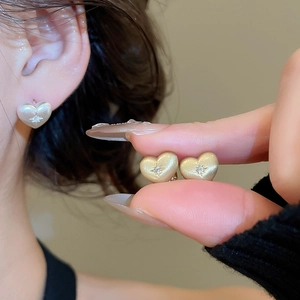 Detailed view of heart-shaped earrings with zircon inlay in gold and silver finishes