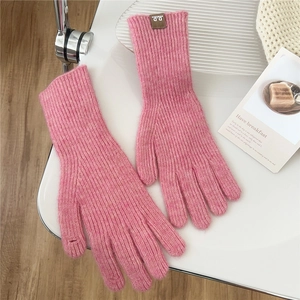 Detail of pink knitted gloves with a small brown leather tag on a soft knit wristband