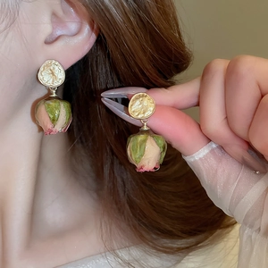 Detail of vintage gold hammered earrings with real dried pink rose bud pendants on a model