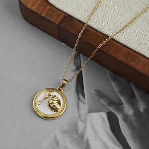 Dettaglio ravvicinato di una collana dorata con medaglione di conchiglia su vassoio