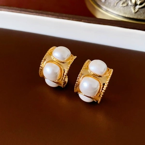 Macro shot of vintage gold-tone C-shape hoop earrings with white pearls and bead trim