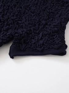 Detailed macro view showing the textured popcorn fabric and refined hem of the knit top
