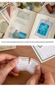 Detail of vintage textured paper stickers being applied to a minimalist journal notebook