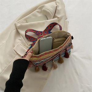 Close-up of bohemian woven shoulder bag with colorful fringe and wide geometric strap