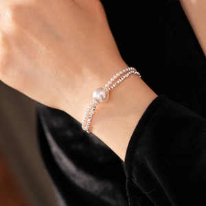 Close-up of double-layer pearl and silver bead bracelet on wrist with velvet backdrop