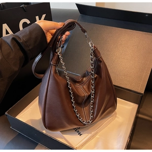 Detail of dark brown leather underarm bag with silver chain and lychee texture