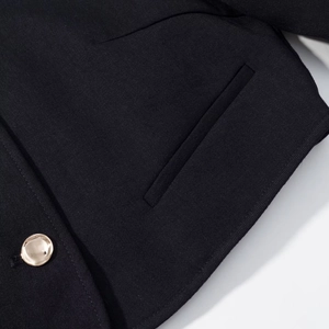 Detail of black twill jacket featuring a luxury golden round metal button and pocket