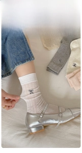 Close-up of ribbed cotton socks featuring elegant black bow embroidery and elastic cuffs