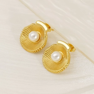 French style 18K gold shell earrings with white pearl inlay on textured white fabric