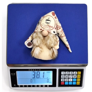 Detailed close-up showing a 38.1g coffee gnome plush on a blue electronic scale