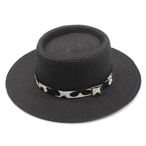 Close-up of black straw sun hat featuring a cow print ribbon and silver buckle detail