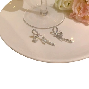 Elegant silver bow earrings with micro-set zircon on white porcelain with a pink rose